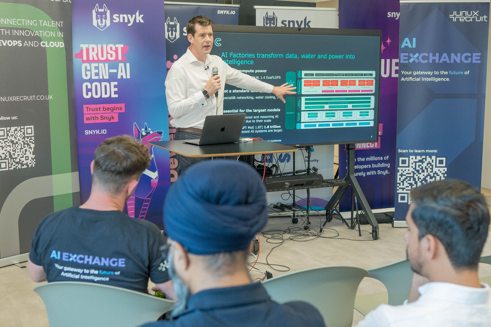 A speaker presenting to a seated audience at an AI Exchange meetup in London
